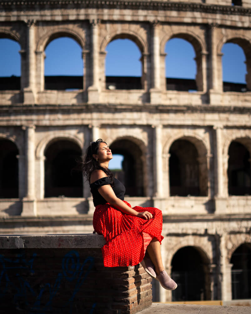 Girl is a red skirt with the colosseum in the background- The colosseum in Rome a must visit on your 10 days in Italy itinerary