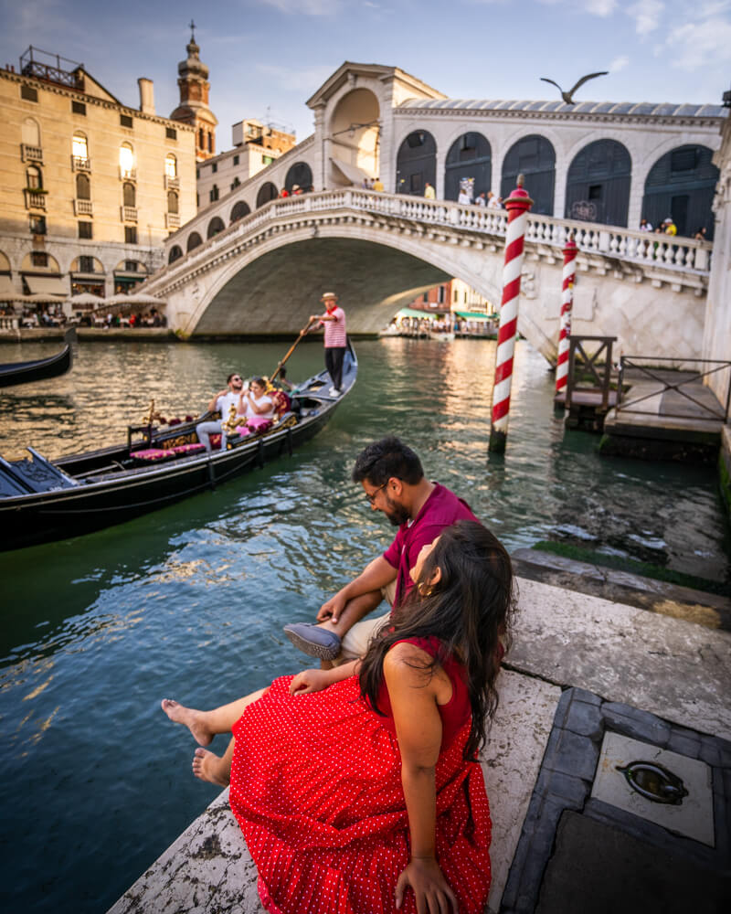 Couple enjoying the view of Rialto Bridge and gondolas in Venice