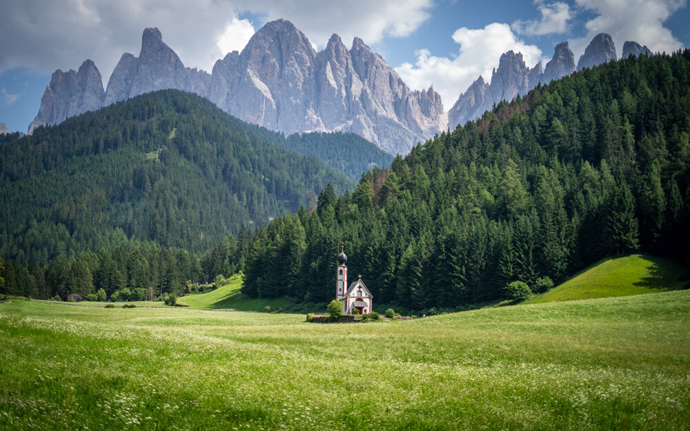 St. John's Church in an idyllic setting complete with meadows, forests, and rugged peaks towering in the background!