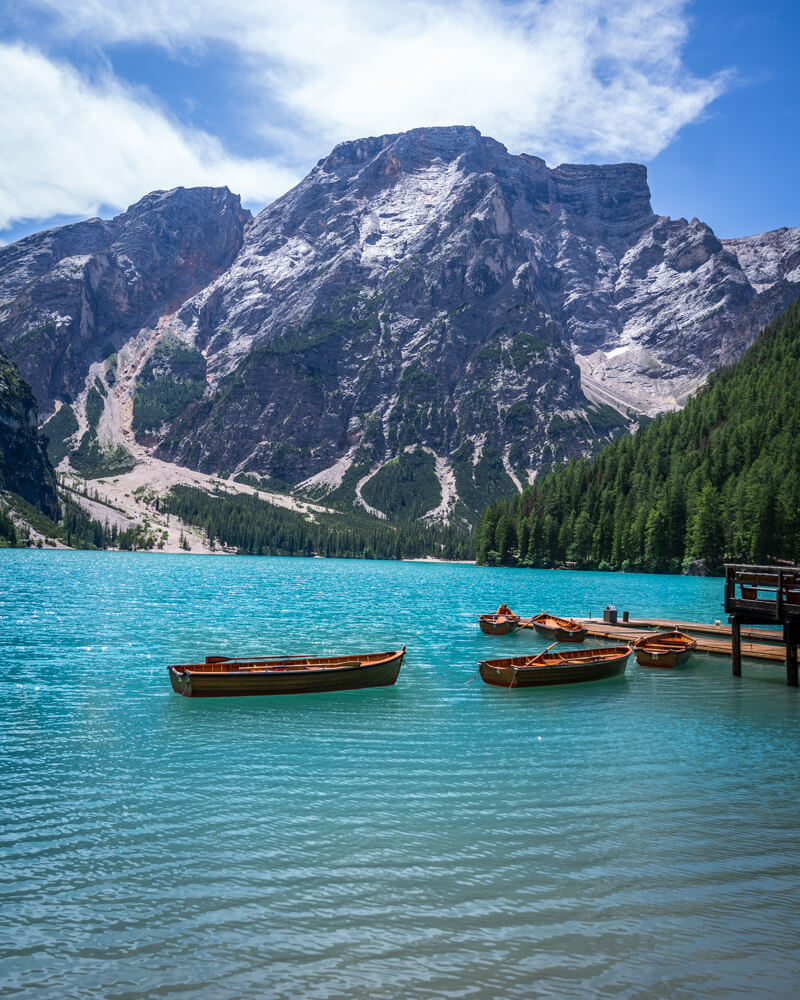 Lago di Braies with its typical but stunning view of boats parked on turquoise blue water with a backdrop of mountains