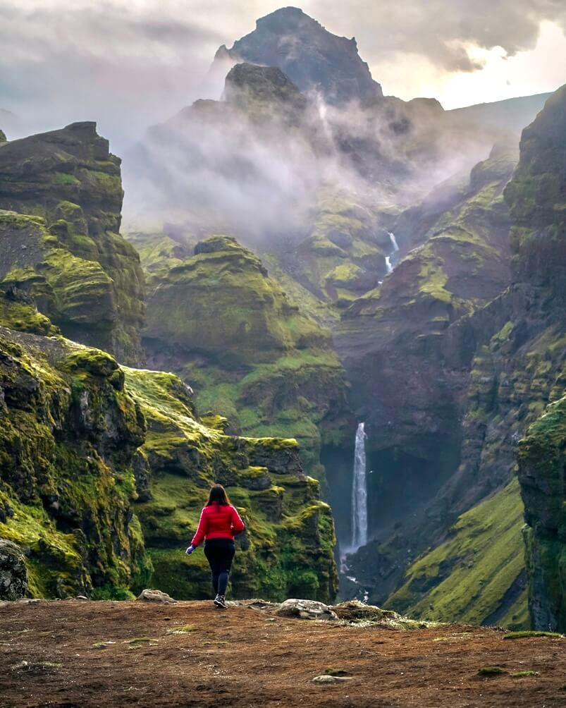 10-Day Iceland Itinerary: An Unforgettable Road Trip 32 A girl admiring the green landscape and waterfall at Mulagljufur Canyon in Iceland