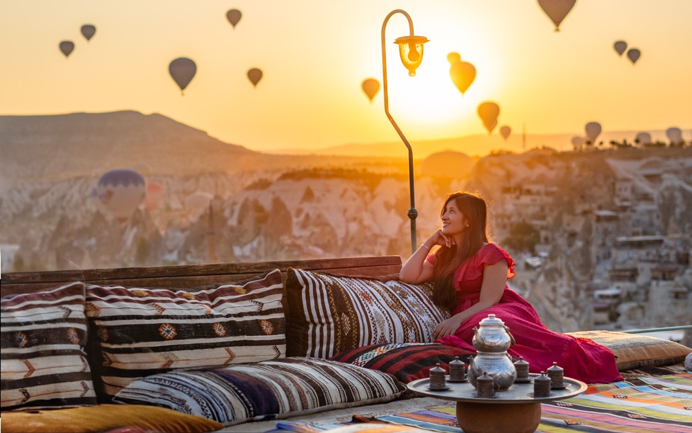 A girl enjoying floating hot air balloon views from the hotel rooftop in Cappadocia Turkey