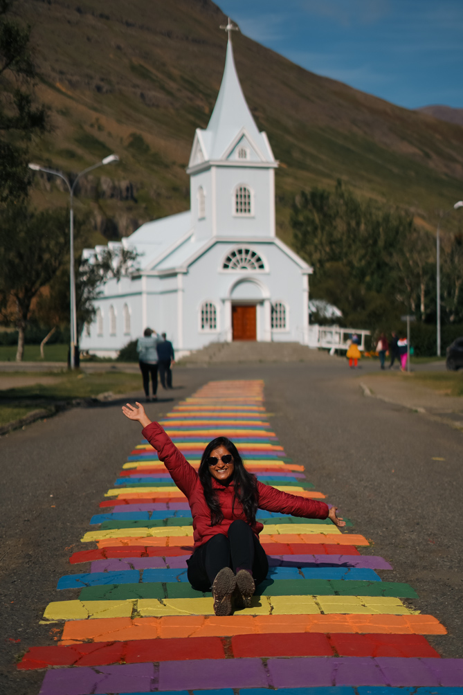 10-Day Iceland Itinerary: An Unforgettable Road Trip 44 Me sitting on the rainbow street at Seydisfjordur that leads to a church