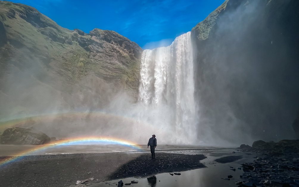 10-Day Iceland Itinerary: An Unforgettable Road Trip 24 A man enjoying the stunning Skogafoss Waterfall. You can see the spray from the waterfall as well as a rainbow!