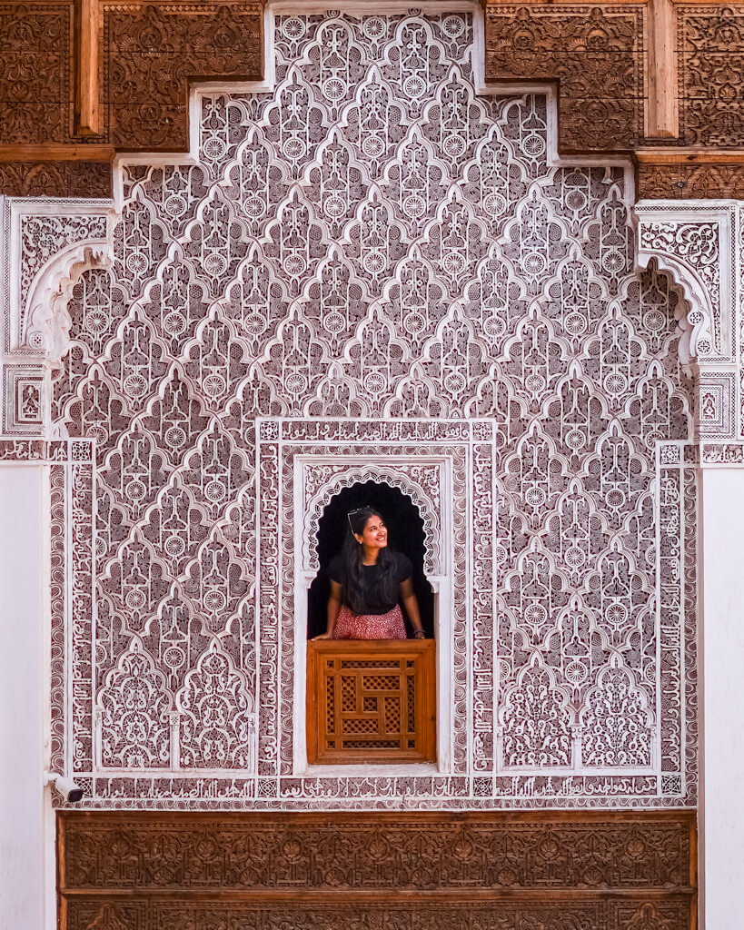 A woman pops her head out of a window with intricate Moroccan work