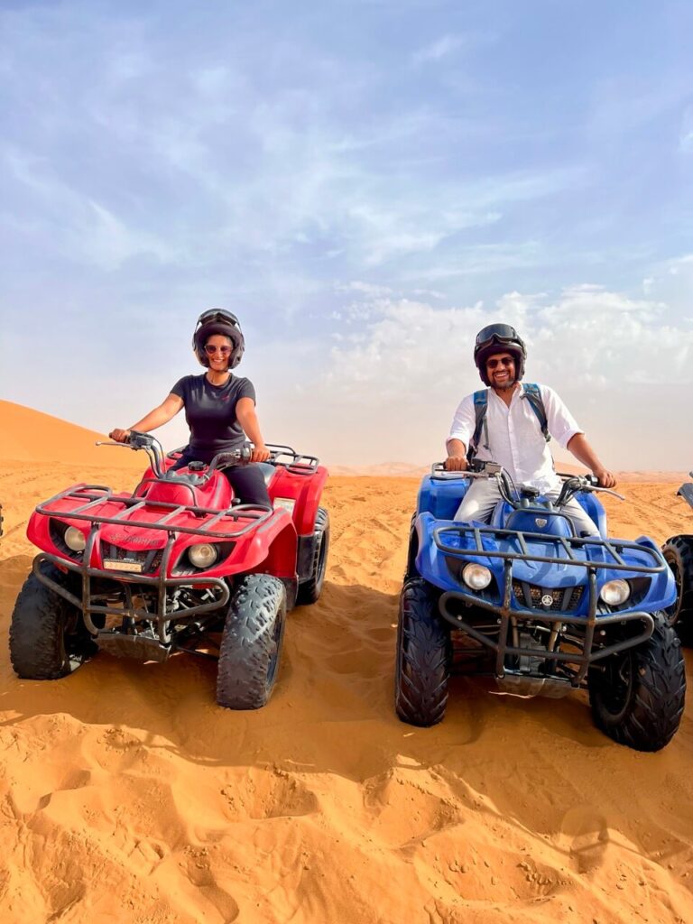 A couple riding ATVs in on the sand dunes
