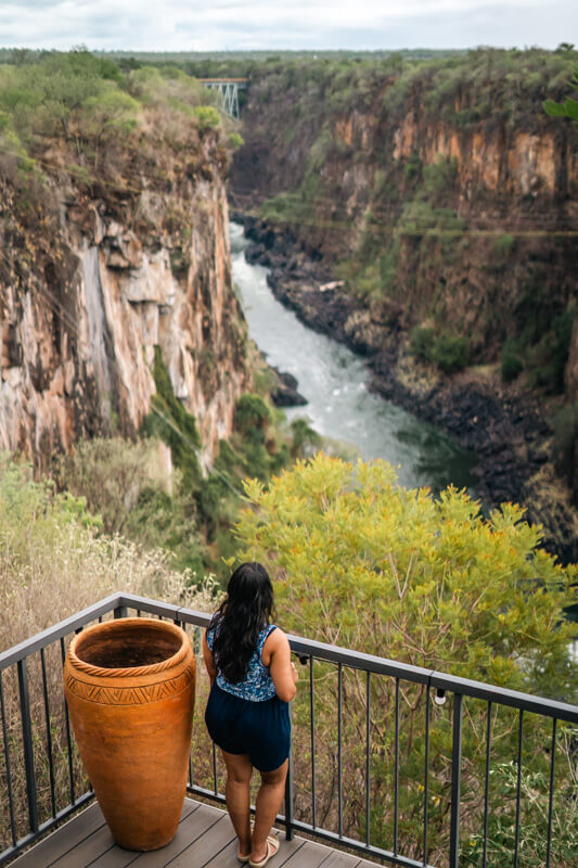 The Perfect 3 Days Victoria Falls Itinerary and Guide 12 A woman in a blue outfit stands on a deck overlooking a deep canyon with a winding river below