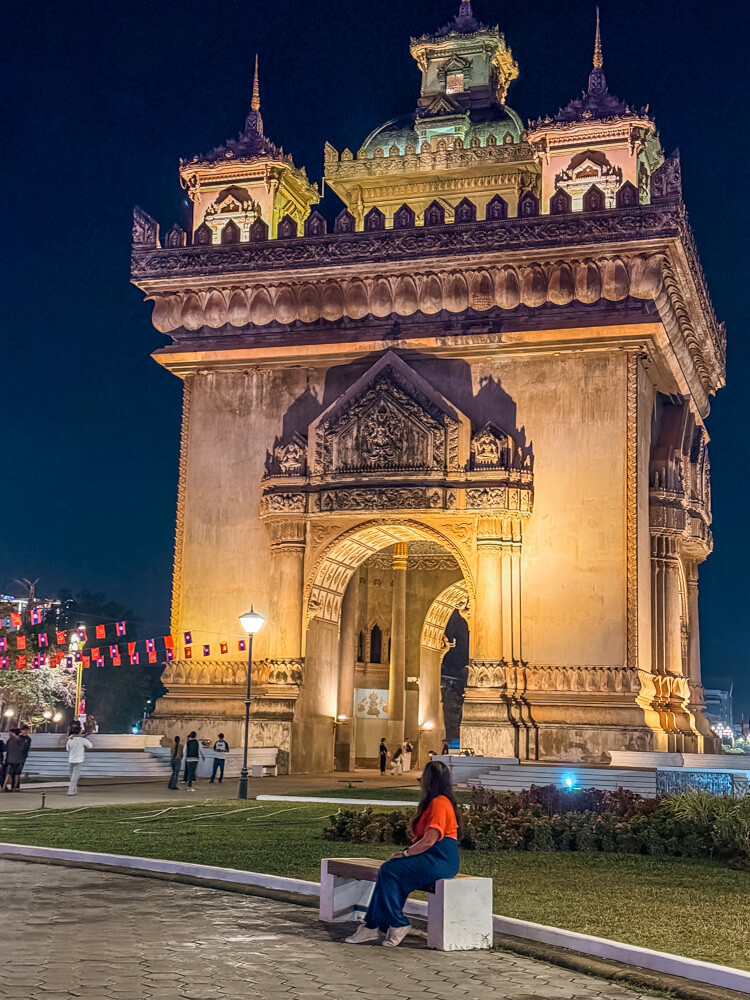 The Only Laos Itinerary You Need for 1 Week in Laos 8 A girl sitting and looking at the Patuxay Monument at night
