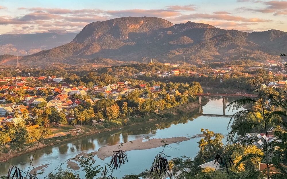 The Only Laos Itinerary You Need for 1 Week in Laos 5 A view of Luang Prabang city as taken from Phousi Hill. You can see the river with a bridge across it, the rooftops of French colonial buildings and the verdant mountains behind