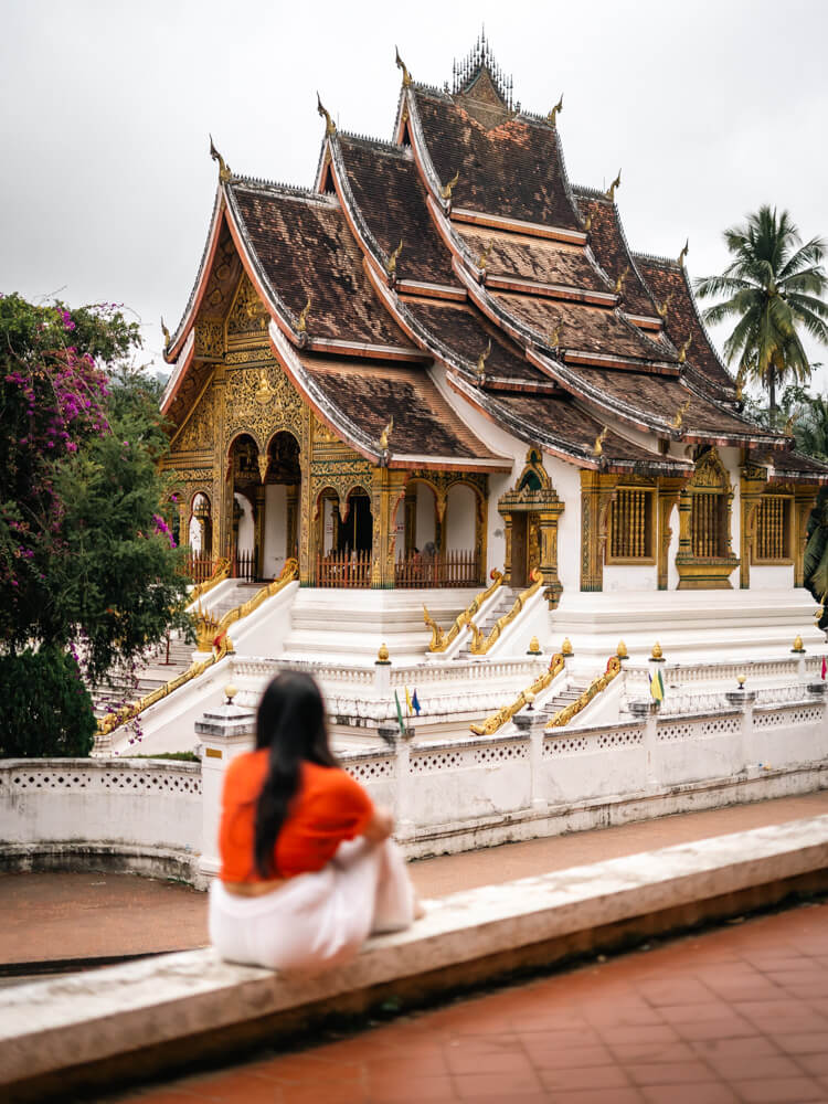 The Only Laos Itinerary You Need for 1 Week in Laos 18 A girl is sitting admiring the Haw Pha Bang Temple at the Royal Palace Museum in Luang Prabang