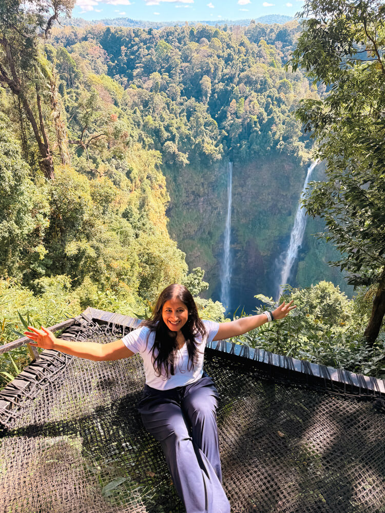 Is Pakse Worth Visiting? 7 Reasons to Go & 3 to Skip It 7 A girls sitting on a net hammock infront of the Tad fane Waterfall