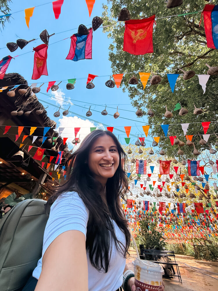 The Only Laos Itinerary You Need for 1 Week in Laos 29 A girl taking a selfie with colourful flags overhead