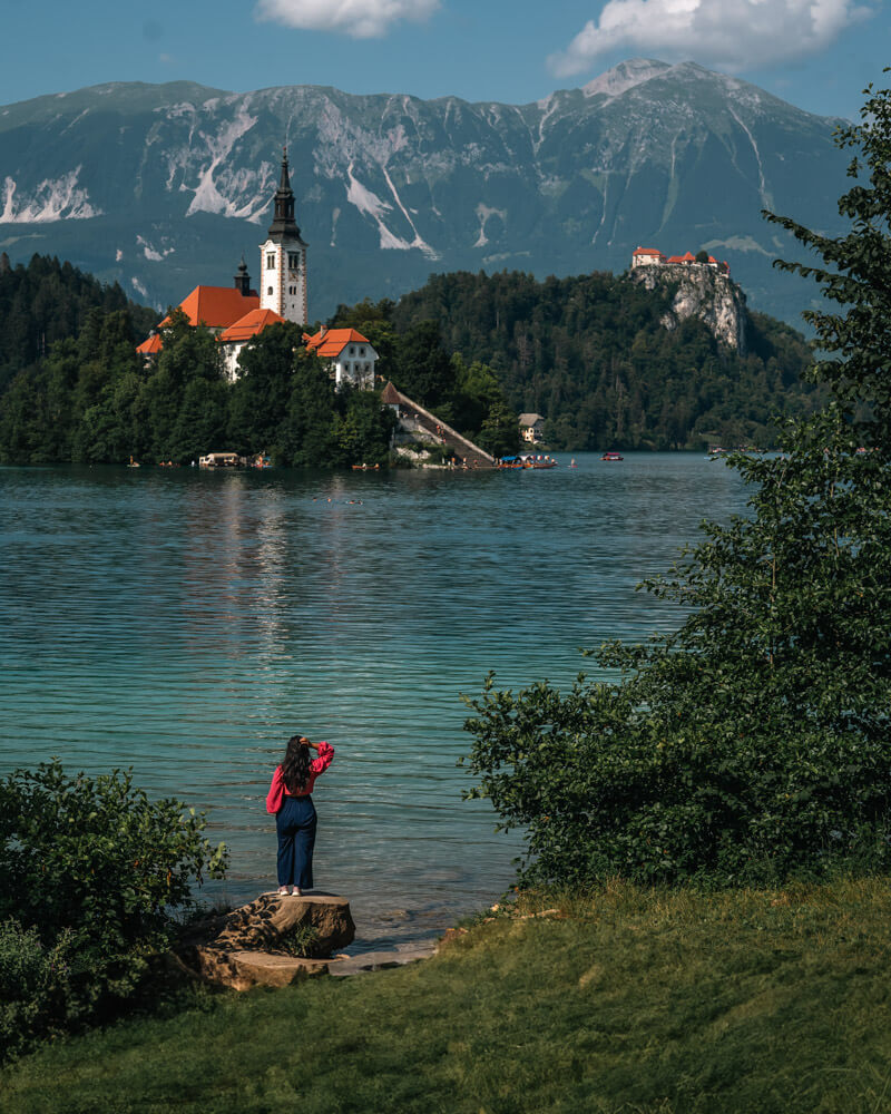 2-Day Lake Bled Itinerary: The Perfect Road Trip Guide 6 A girls in the foreground looking towards Lake Bled's island and castle