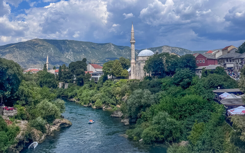 Day Trip to Mostar from Split or Dubrovnik (How to Plan It) 21 A picture-perfect view from Stari Most bridge of the river, mosque, town houses and the mountains