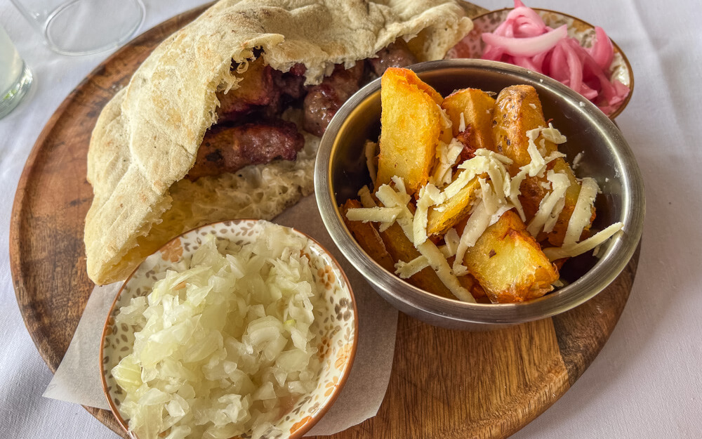 Day Trip to Mostar from Split or Dubrovnik (How to Plan It) 18 A photo of cevapi kebabs in a pita pocket, potato wedges and white onions