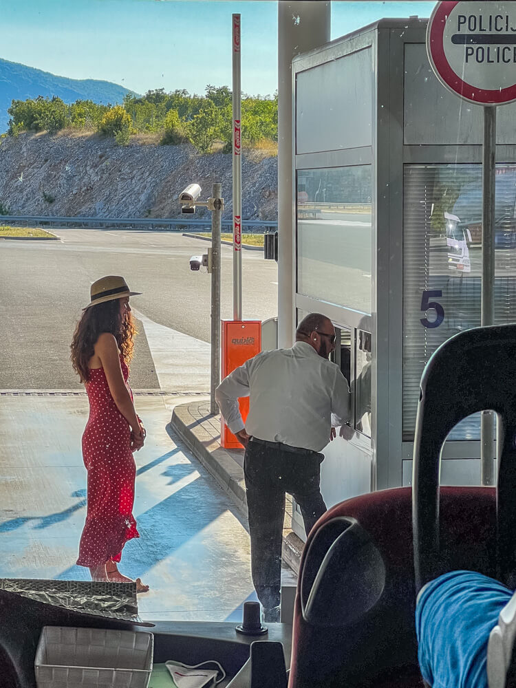Day Trip to Mostar from Split or Dubrovnik (How to Plan It) 9 A woman in a red polka dot dress standing at a border crossing