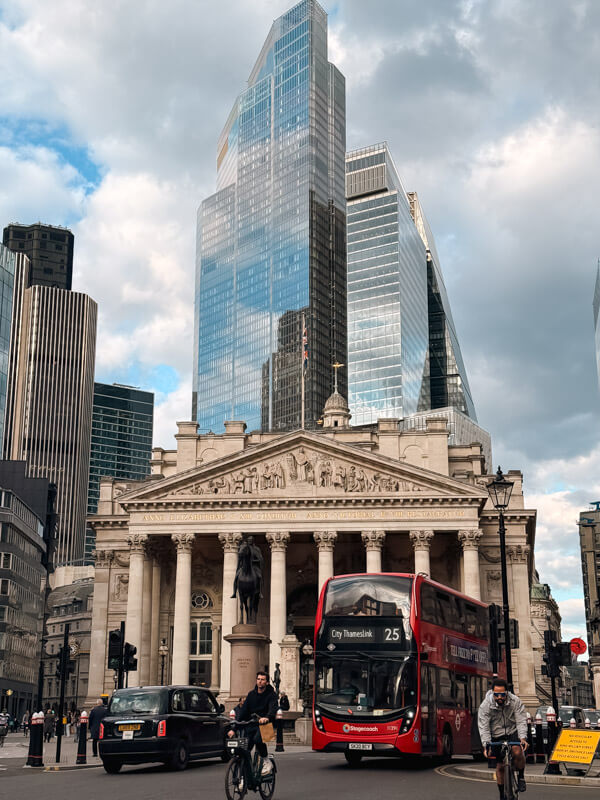 4-Day London Itinerary: Best of London + Easy Walking Routes 28 A view of a London double-decker bus along with other traffic passing by with a backdrop of the Royal Exchange and modern glass skyscrapers behind