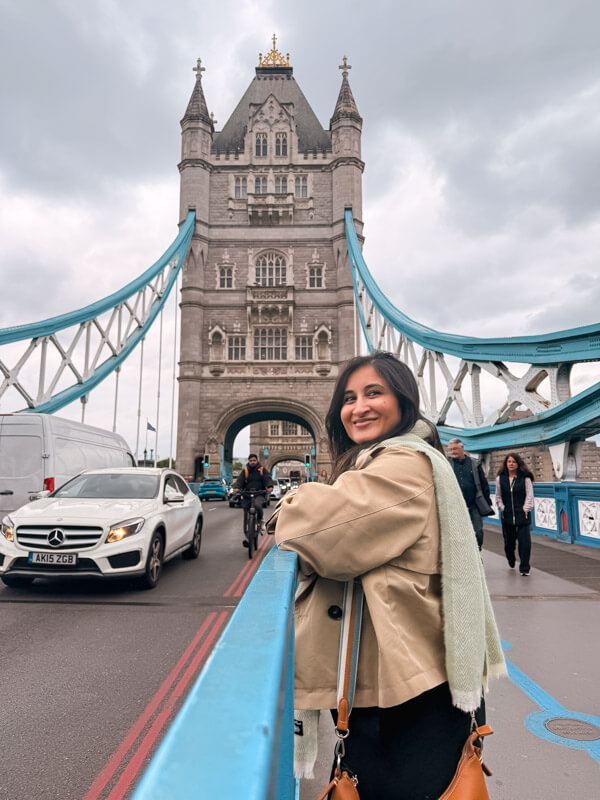 4-Day London Itinerary: Best of London + Easy Walking Routes 12 A woman in a beige coat smiles while standing in the pedestrian section of the Tower Bridge.