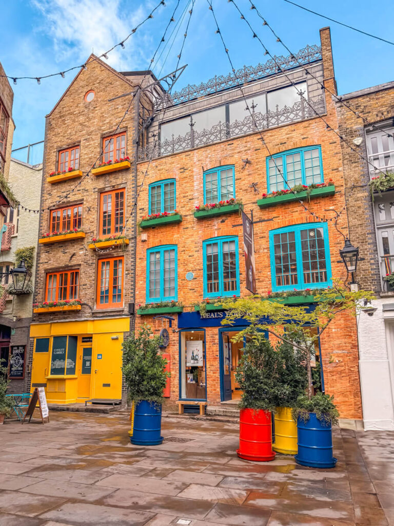 4-Day London Itinerary: Best of London + Easy Walking Routes 17 Neal's Yard in Covent Garden, a hidden colourful courtyard with brightly painted shopfronts, blue and orange window frames, and potted plants in painted barrels.