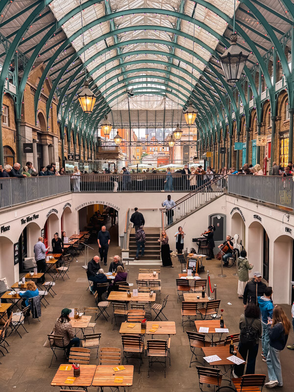 4-Day London Itinerary: Best of London + Easy Walking Routes 18 The covered market at Covent Garden. People are sitting and eating and an buskers perform their instrumental music