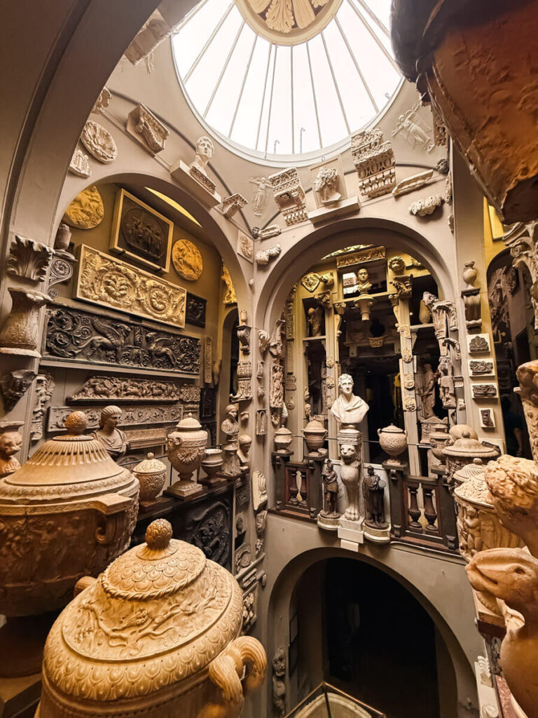 ensely packed collection of classical busts, urns, and stone reliefs inside Sir John Soane's Museum, lit by a domed glass skylight.