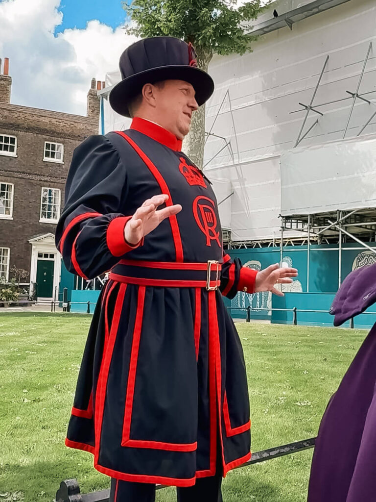 7 Best Paid Attractions in London Actually Worth Paying For 6 A Yoeman Warder dressed in black and red with a black hat telling stories of the Tower of London